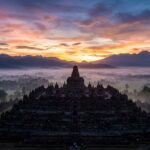 Sunrise over Borobudur Temple with mist and volcanoes in the background
