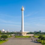 Top 10 Must-Visit Attractions in Jakarta (2025 Guide) A wide view of the National Monument (Monas) in Jakarta, with a clear blue sky and lush green trees.