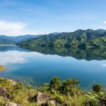 A wide view of Lake Tuba surrounded by green hills under a bright sky.