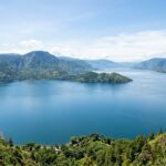 Things to Do in Lake Toba: Top Attractions & 2025 Travel Guide A wide shot of Lake Toba with Samosir Island in the distance, under a clear sky.