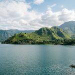 Visiting Lake Toba: 5 Essential Tips for Your 2025 Trip A wide view of Lake Toba with Samosir Island and surrounding mountains under a bright sky.