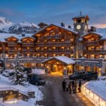 Best Hotels in Courchevel 1850: Luxury Ski Stays (2026) A luxurious hotel in Courchevel 1850 at dusk, with warm lights glowing against the snow.